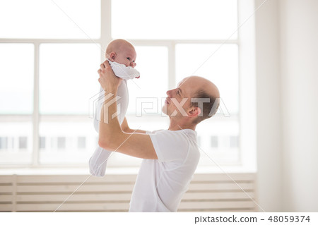 Parenting, family and fatherhood concept - cute bald dad and baby daughter hugging over window Parenting, family and fatherhood concept - cute bald dad and baby daughter hugging over window 48059374