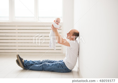 Parenting, family and fatherhood concept - Bald father sitting on the floor and hold his little baby 48059377