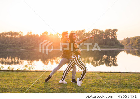 Kizomba, bachata, zouk and latin social dance concept - Man and woman dancing over nature background Kizomba, bachata, zouk and latin social dance concept - Man and woman dancing over nature background 48059451
