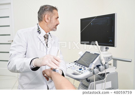 Doctor doing ultrasound examination of patinet's wrist. 48059759