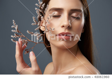 Attractive girl holding beautiful sprigs with tiny white flowers near her face 48061960