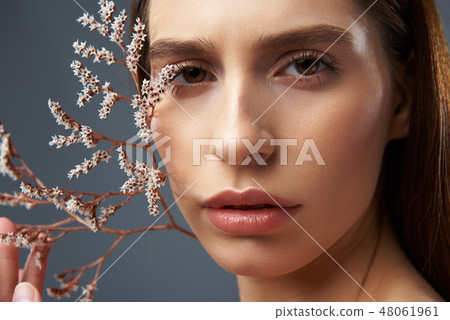 Charming girl holding beautiful sprigs with white flowers near her face 48061961