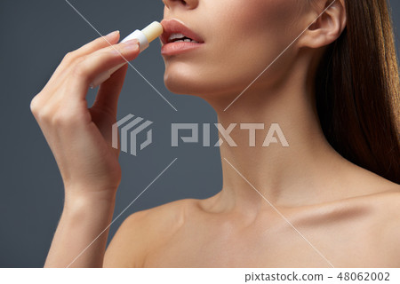 Young lady with beautiful full lips using hygienic lipstick Young lady with beautiful full lips using hygienic lipstick 48062002