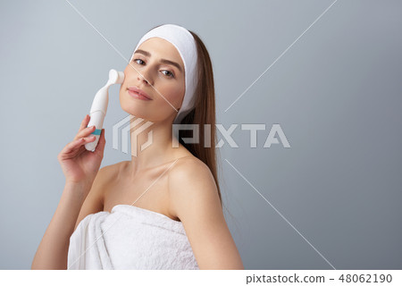 Beautiful young lady using pore cleansing brush after bath Beautiful young lady using pore cleansing brush after bath 48062190