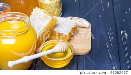 Honey with wooden honey dipper on wooden table 48062417