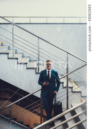 Attractive man with suitcase and telephone on stairs 48062665