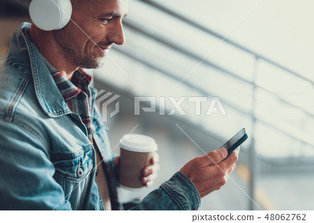 Man with cellular and beverage enjoying his music 48062762