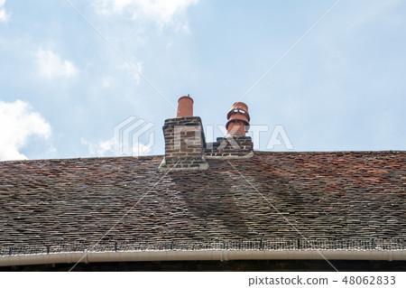 突出在磚瓦房的屋頂的煙囪在藍天下 48062833