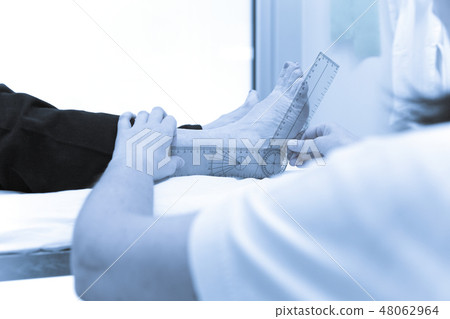 Doctor or physiotherapist meausuring active range Doctor or physiotherapist meausuring active range 48062964