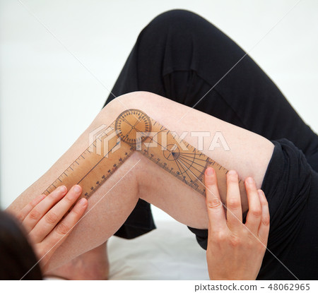 Doctor or physiotherapist meausuring active range Doctor or physiotherapist meausuring active range 48062965