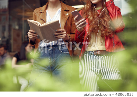 Two stylish young women spending time outdoors Two stylish young women spending time outdoors 48063035