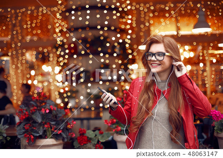 Charming red-haired girl holding cellphone and listening music 48063147