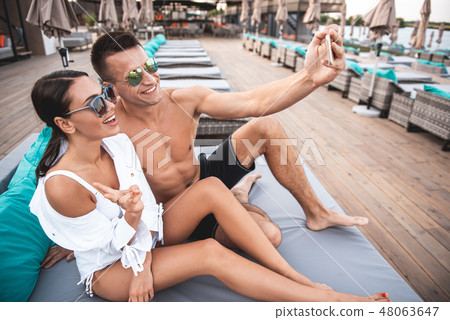 Happy young couple smiling while taking selfies Happy young couple smiling while taking selfies 48063647