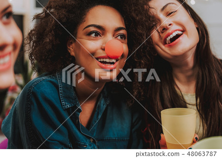 Beaming mulatto female situating near caucasian friend 48063787