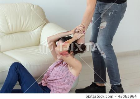 domestic violence, victim and abuse concept - cruel aggressive man grabbing woman lying on the floor domestic violence, victim and abuse concept - cruel aggressive man grabbing woman lying on the floor 48063964