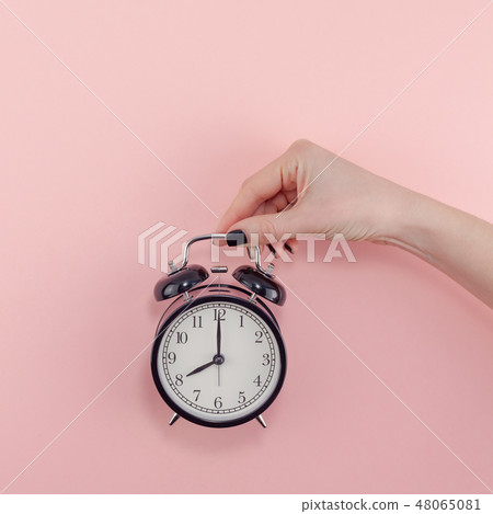 Female hand with alarm clock. Morning concept Female hand with alarm clock. Morning concept 48065081