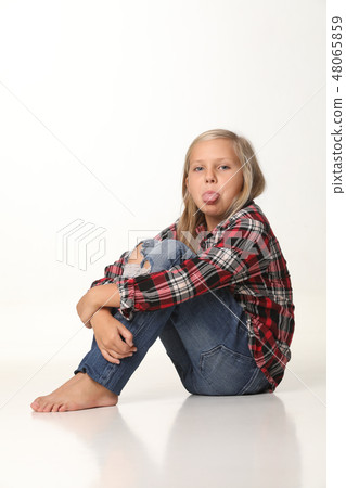 Girl with long blond hair showing his tongue sitting on the floor. White background 48065859