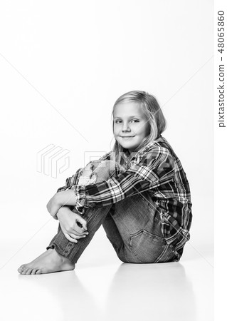 Photo black and white cute girl sitting on the floor and smiling sincerely. White background 48065860