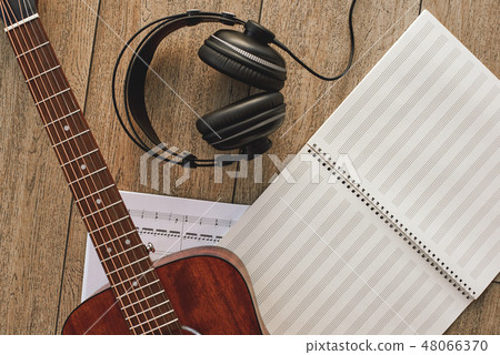 Close up view of guitar, professional headphones and musical notes laying on the wooden floor 48066370