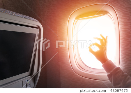 Woman doing thumbs up in front of airplane window 48067475