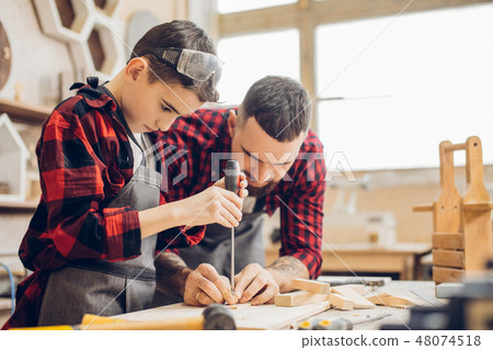 Father and little son at wooden workshop using screwdriver. Father and little son at wooden workshop using screwdriver. 48074518