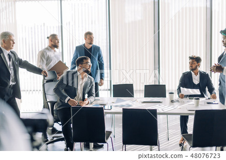 Indian customer debats with Arabian contractor sitting against panoramic window Indian customer debats with Arabian contractor sitting against panoramic window 48076723