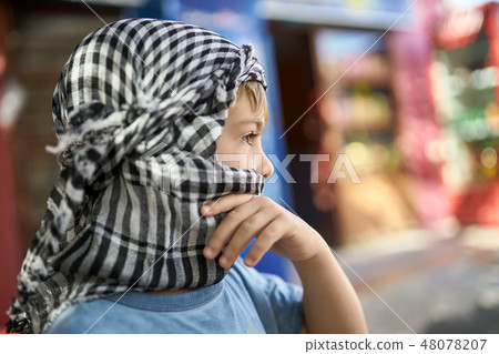 Small boy in checkered keffiyeh posing outdoors 48078207