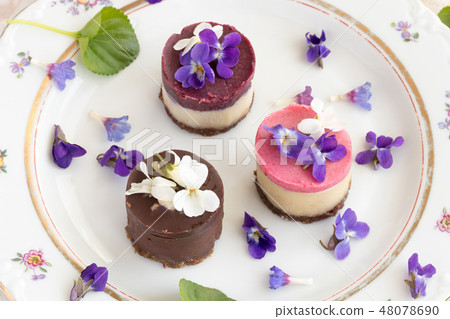 Raw vegan desserts on a plate with violet flowers 48078690