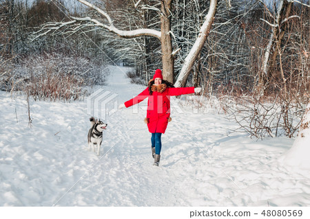 Young woman playing with her Husky dog in winter park Young woman playing with her Husky dog in winter park 48080569