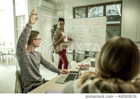 Blonde student wearing glasses raising hand having question Blonde student wearing glasses raising hand having question 48080636