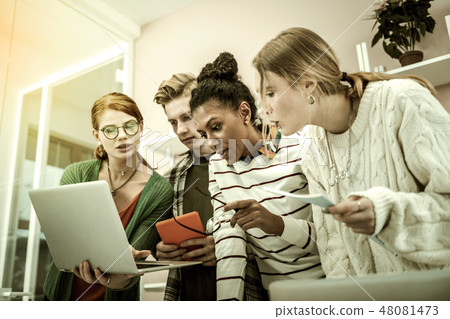 Four office workers working on the same project feeling busy 48081473