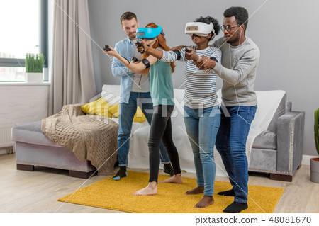 Multicultural group of friends playing games using virtual reality glasses. Multicultural group of friends playing games using virtual reality glasses. 48081670
