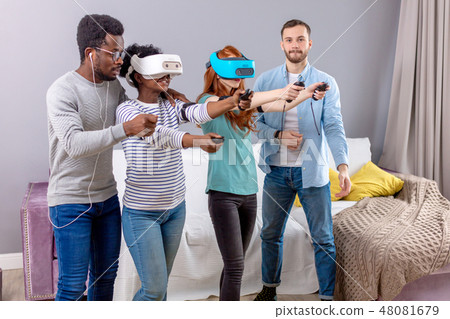 Multicultural group of friends playing games using virtual reality glasses. 48081679