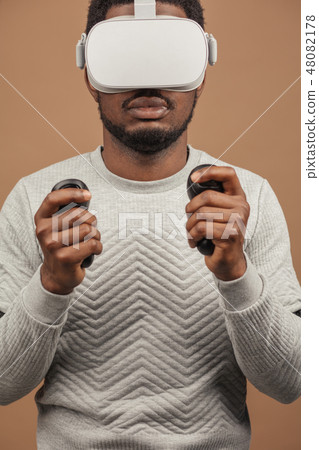 Black man wearing 3d vr glasses, playing videogame, holding joystick in hands Black man wearing 3d vr glasses, playing videogame, holding joystick in hands 48082178