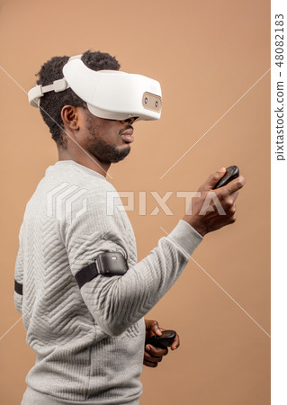 Black man wearing 3d vr glasses, playing videogame, holding joystick in hands Black man wearing 3d vr glasses, playing videogame, holding joystick in hands 48082183
