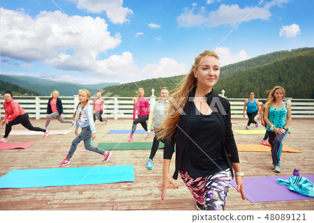 Beautiful woman coaching fitness group on fresh air. 48089121