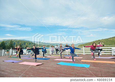 Flexible girls doing balance exercises outdoors. 48089154