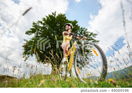 Attractive female cyclist with yellow mountain bicycle, enjoying sunny day in the mountains 48089596
