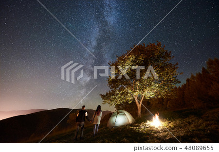 Couple tourists resting at night camping under stars Couple tourists resting at night camping under stars 48089655