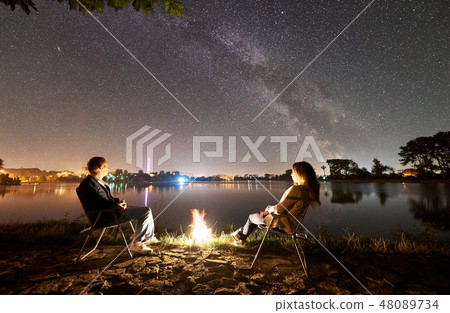 Man and woman having a rest on shore under night sky 48089734