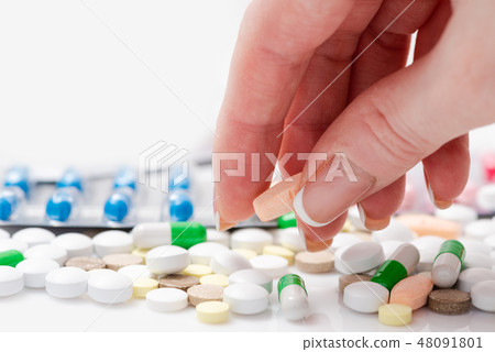 Close-up of female hand holding a pink pill Close-up of female hand holding a pink pill 48091801