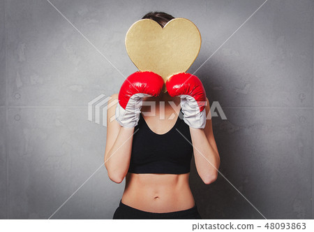 woman in boxing gloves with heart shape gift box in hands woman in boxing gloves with heart shape gift box in hands 48093863
