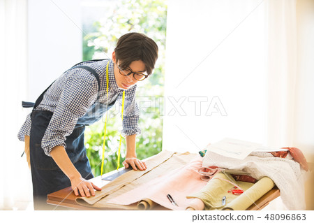 A man sewing 48096863