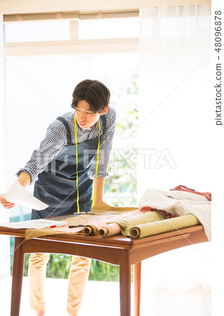 A man sewing 48096878