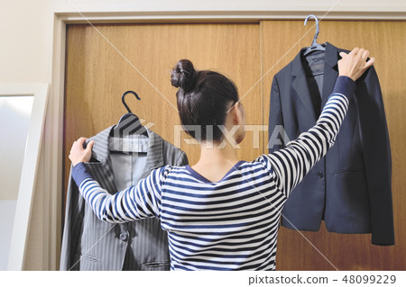 Women picking a suit jacket Women picking a suit jacket 48099229