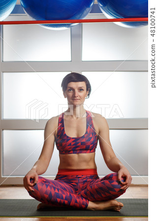 Young sporty woman doing Sukhasana exercise 48100741