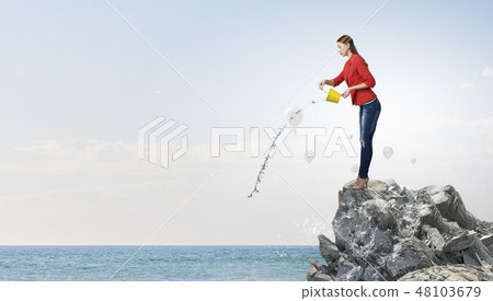 Girl pouring water from bucket 48103679