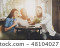 A company of friends sits in a cafe at the table 48104027