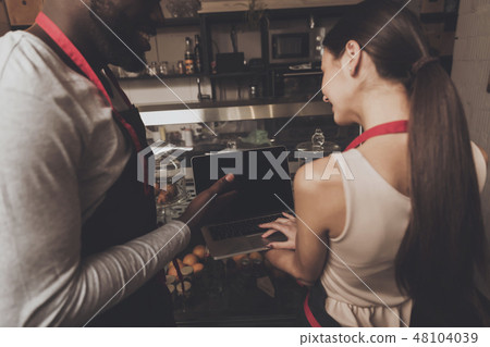 Barista man and woman looking at a laptop 48104039