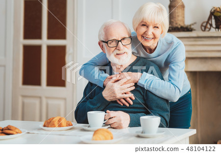 Cute couple of pensioners having warm croissants during breakfast Cute couple of pensioners having warm croissants during breakfast 48104122